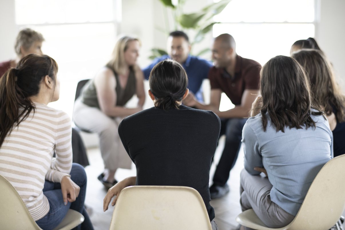 A group of coworkers seated in a circle of chairs, talking