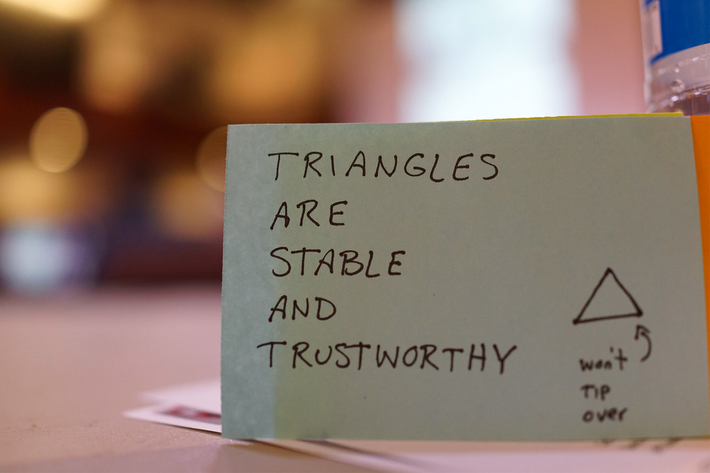 A handwritten sticky note reading 'Triangles are stable and trustworthy' with a small triangle sketch labeled 'won't tip over'.